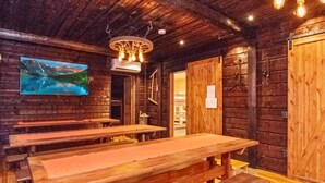Un intérieur rustique en bois, avec des bancs en bois et un téléviseur fixé au mur qui diffuse des images d’un paysage pittoresque.