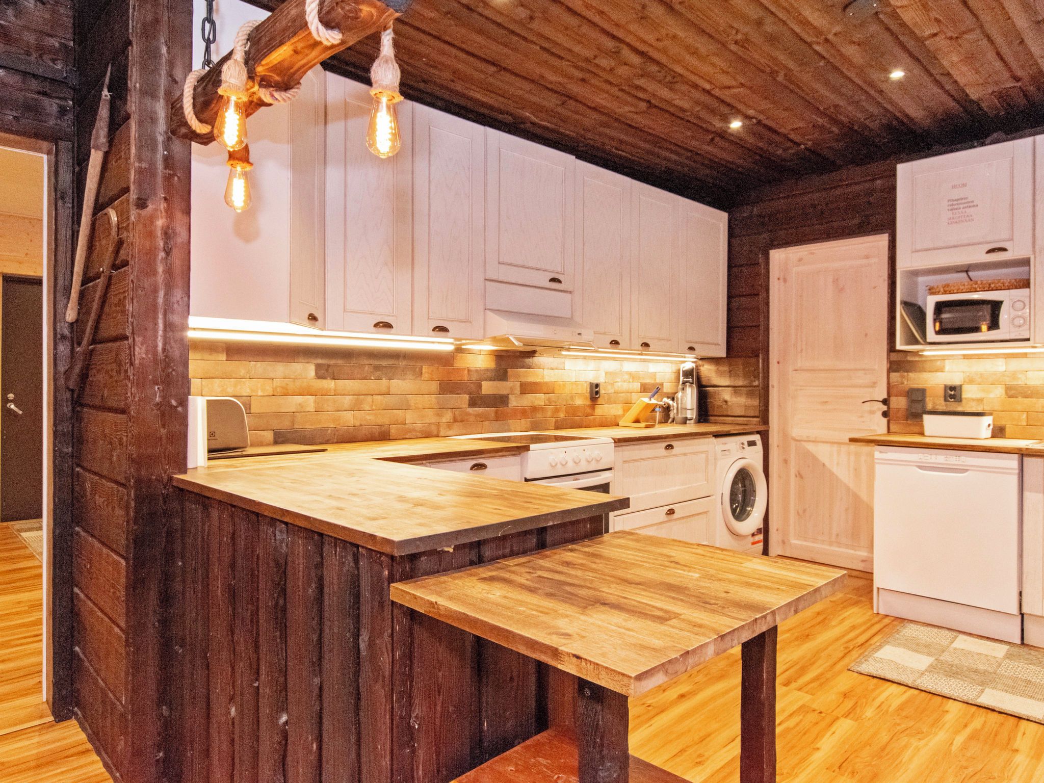 Una cocina con armarios de madera, una isla central y una lámpara colgante.