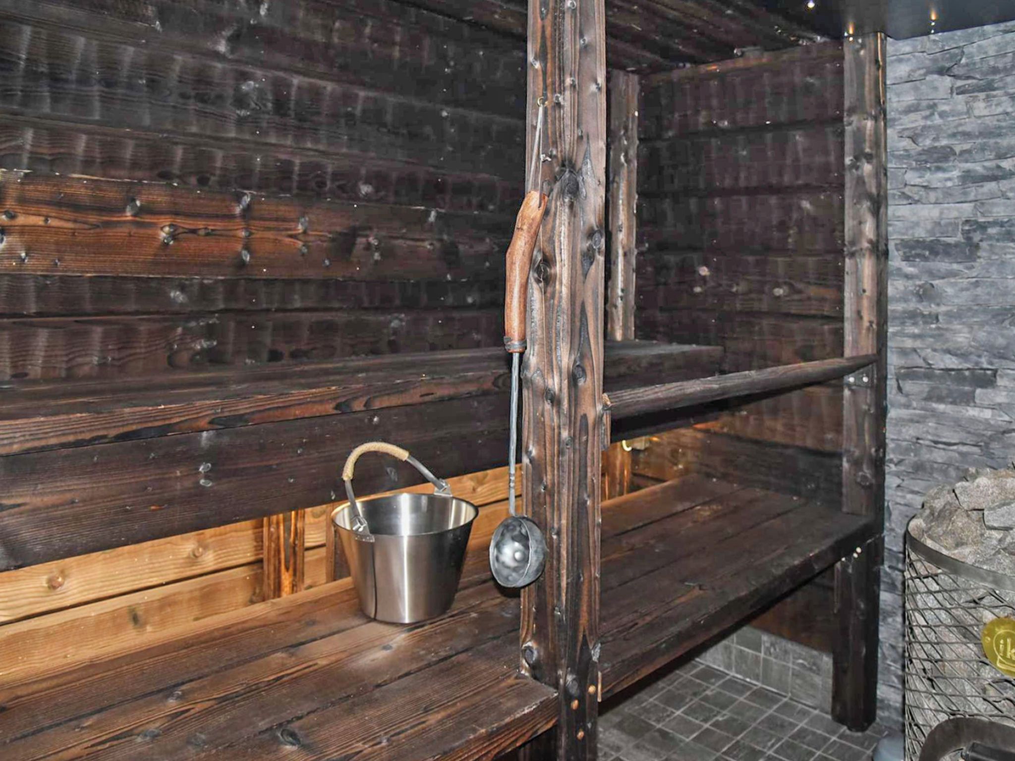 Un intérieur rustique en bois, avec un seau en métal posé sur une étagère.