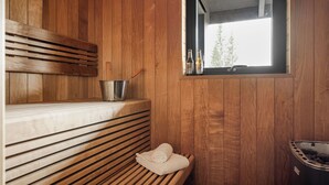 A sauna room with wooden benches, a window, and a sauna tub.