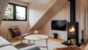 A cozy loft bedroom with a sloped ceiling, a fireplace, a TV, and a comfortable seating area.