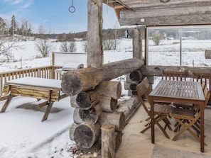 An outdoor wooden deck with a grill and seating area, surrounded by snow-covered ground and trees. - Kaislaranta by Interhome (Salo)