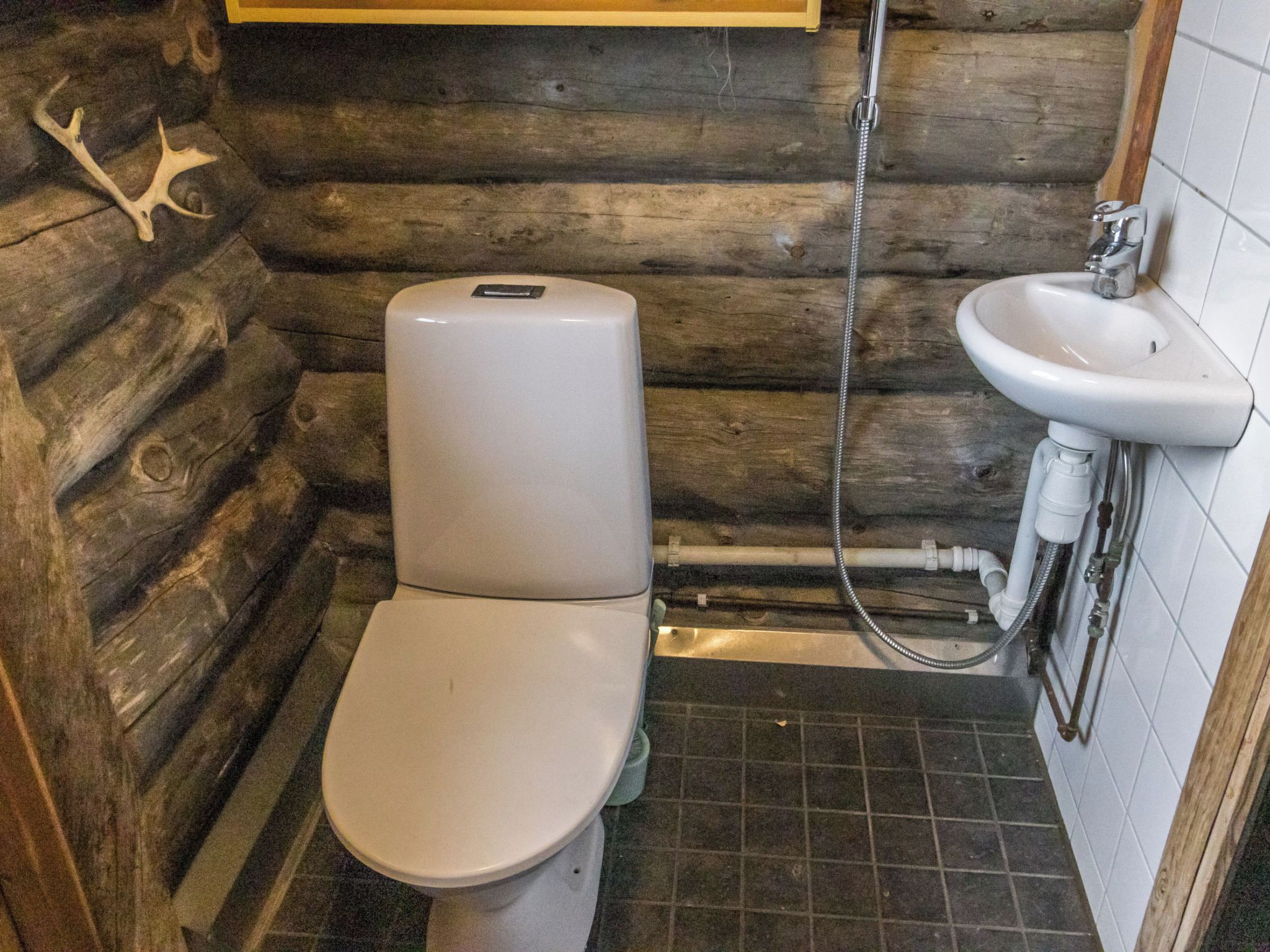 Un bany petit i rústic amb vàter, rentapel i plat de dutxa.