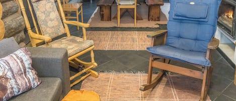 L’intérieur d’un chalet rustique, avec un mur en pierre, des meubles en bois, une cheminée et un coin cuisine.