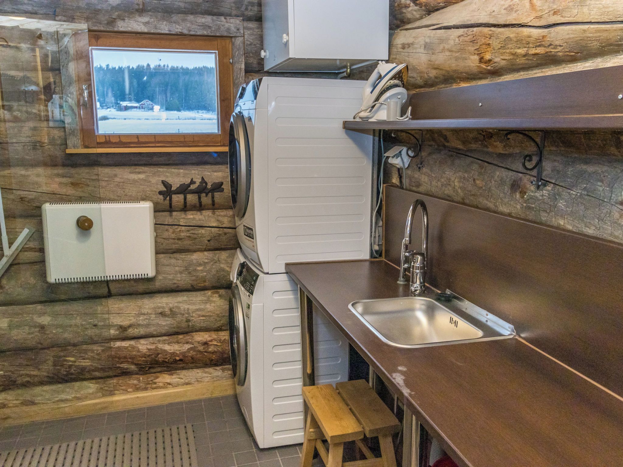 A compact kitchen with a sink, a refrigerator, and a window with a view of a snowy landscape.