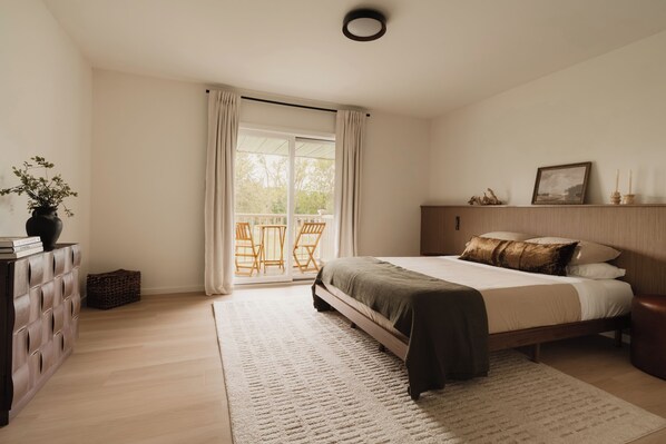 A bedroom with a bed, a dresser, a window with curtains, and a view of the outdoors.