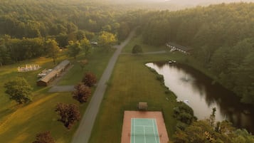Vista aèria d'una propietat amb una pista de tennis, un riu i una zona forestal.