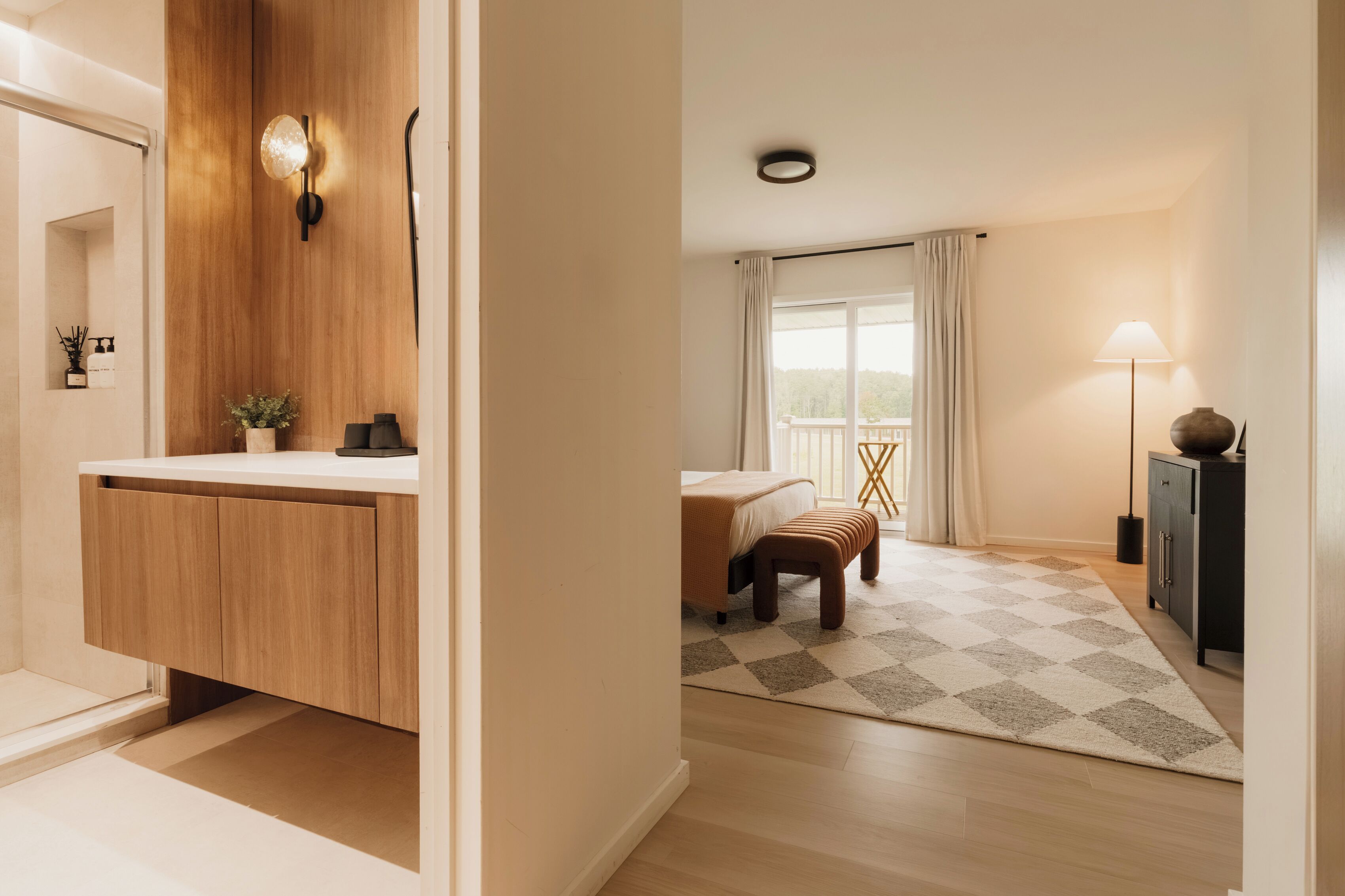 A modern bathroom with a wooden vanity, a shower area, and a small plant.