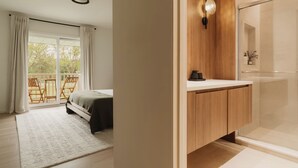 Un dormitorio moderno con una cama grande, un armario de madera y un box de ducha de vidrio.