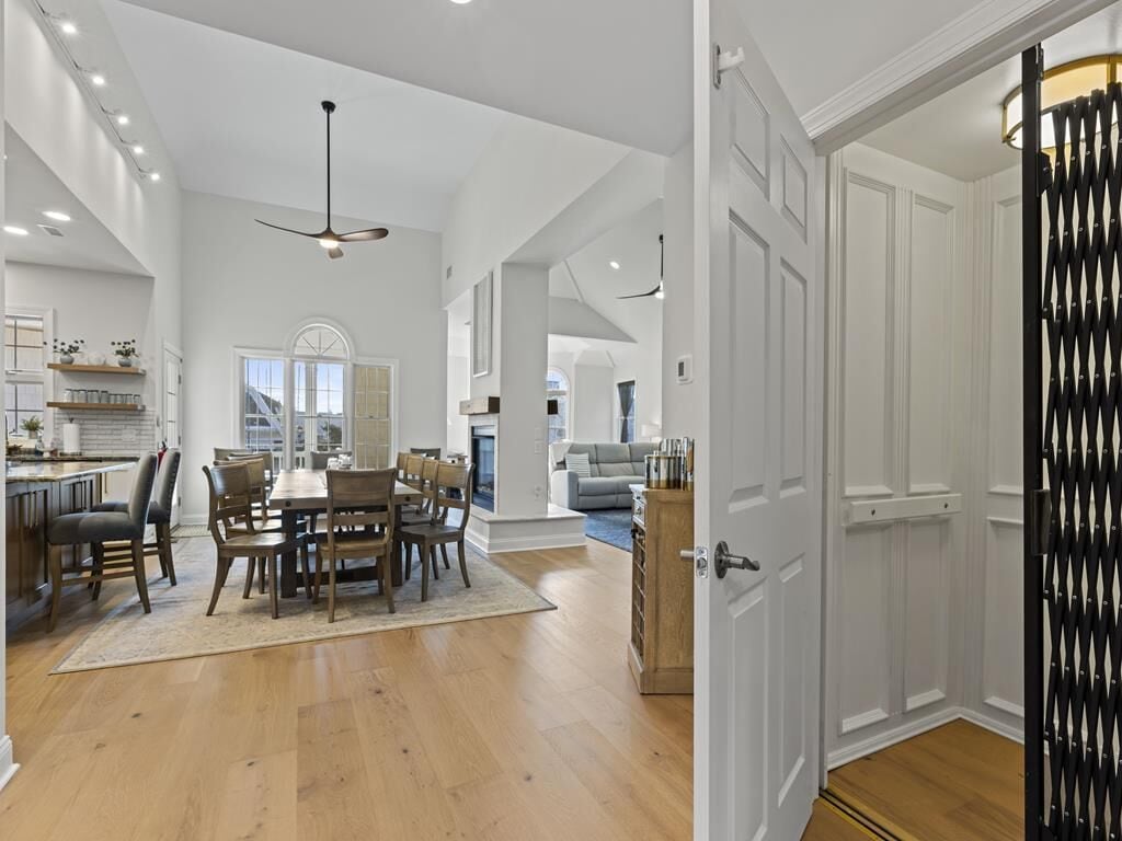 A spacious kitchen with a dining area, wooden flooring, and a modern ceiling fan.