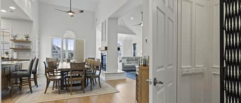 A spacious kitchen with a dining area, wooden flooring, and a modern ceiling fan.