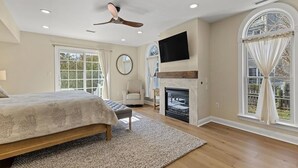 A spacious bedroom with a large bed, a fireplace, a ceiling fan, and a TV mounted on the wall. - 7 Bedroom, 4 Full Baths, and Two Blocks to Beach (Cape May)