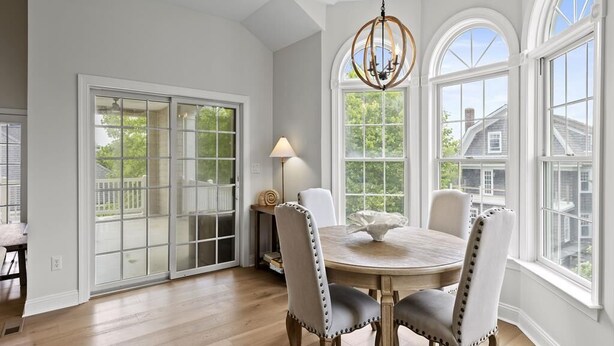 A dining room with a round table, four chairs, and a chandelier. There are large windows with arched tops and a view of the outside. - 7 Bedroom, 4 Full Baths, and Two Blocks to Beach (Cape May)