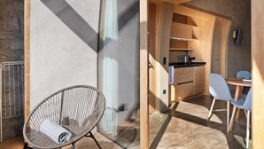 A modern interior with a wicker chair, a wooden dining table with chairs, and a kitchen area. - Studio 'Pavilion Earth' with Mountain View, Shared Terrace and Wi-Fi (Velturno)