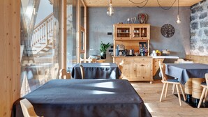 A restaurant with wooden tables and chairs, a kitchen area, and a stone wall. - Studio 'Pavilion Earth' with Mountain View, Shared Terrace and Wi-Fi (Velturno)