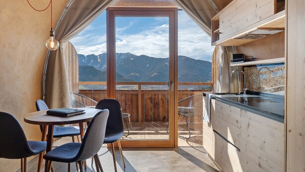 Une cuisine compacte avec vue sur les montagnes, un coin repas avec des chaises et une table.