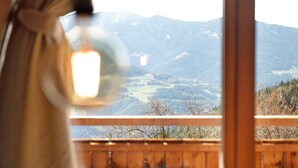 Une vue sur les montagnes depuis un balcon en bois, avec un ciel dégagé.