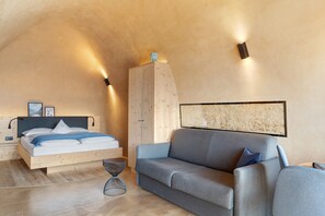 Une chambre confortable avec un lit, un canapé, une petite table et un luminaire fixé au mur.
