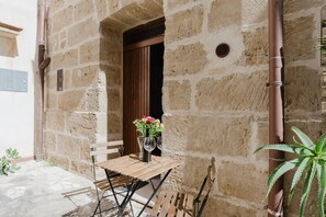 Un edificio in pietra con un tavolo e sedie di legno, un vaso con fiori e una pianta in vaso.