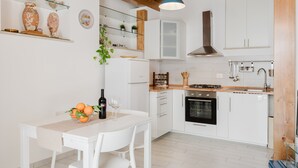 A modern kitchen with white cabinets, a wooden ceiling, and a dining area with a table set for two.