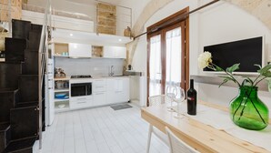 Une cuisine moderne avec des meubles blancs, un plan de travail en bois et un coin repas comprenant une table et des chaises.