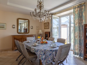 Una sala da pranzo con un lampadario, un tavolo imbandito per quattro persone e vista all'esterno attraverso ampie finestre.