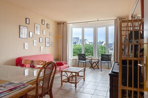 A living room with a sofa, chairs, a coffee table, and a view through large windows.