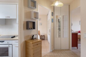 Une cuisine avec des meubles blancs, une cuisinière et une horloge fixée au mur.