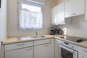 Una cocina con ventana, un lavabo, una cafetera y un horno.