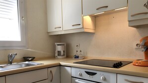 Eine Küche mit weißen Schränken, einer Kaffeemaschine, einem Spülbecken und einem Backofen.