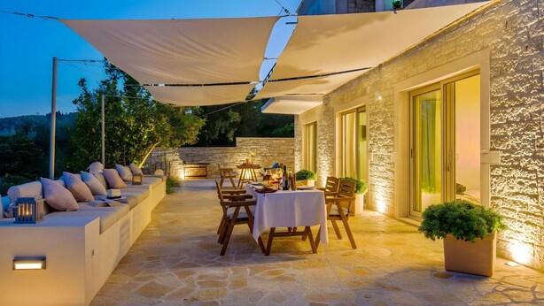 An outdoor patio with stone flooring, a sofa, a table, and chairs.