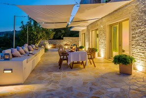 An outdoor patio with stone flooring, a sofa, a table, and chairs.