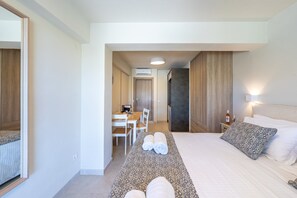 A hotel room with a bed, a bedside table, a lamp, a desk with a chair, and a bathroom visible through an open door. - Studio Apartment 'Katerina' with Mountain View, Wi-Fi and Air Conditioning (Gaios)