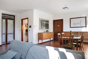 A living room with a sofa, dining table with chairs, a cabinet, and a painting on the wall.