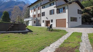 A two-story house with a stone facade, a wooden deck, and a view of a mountain. - Apartment 'Casa Letizia' with Private Pool, Private Terrace and Wi-Fi (Colico)