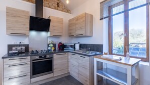 Una cocina moderna con armarios de madera, horno empotrado, microondas y una ventana con persianas.