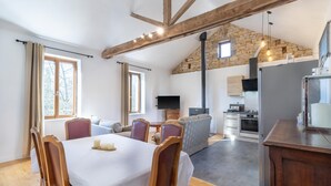 Amplia sala de estar con mesa de comedor, sillas, sofá y zona de cocina con electrodomésticos.