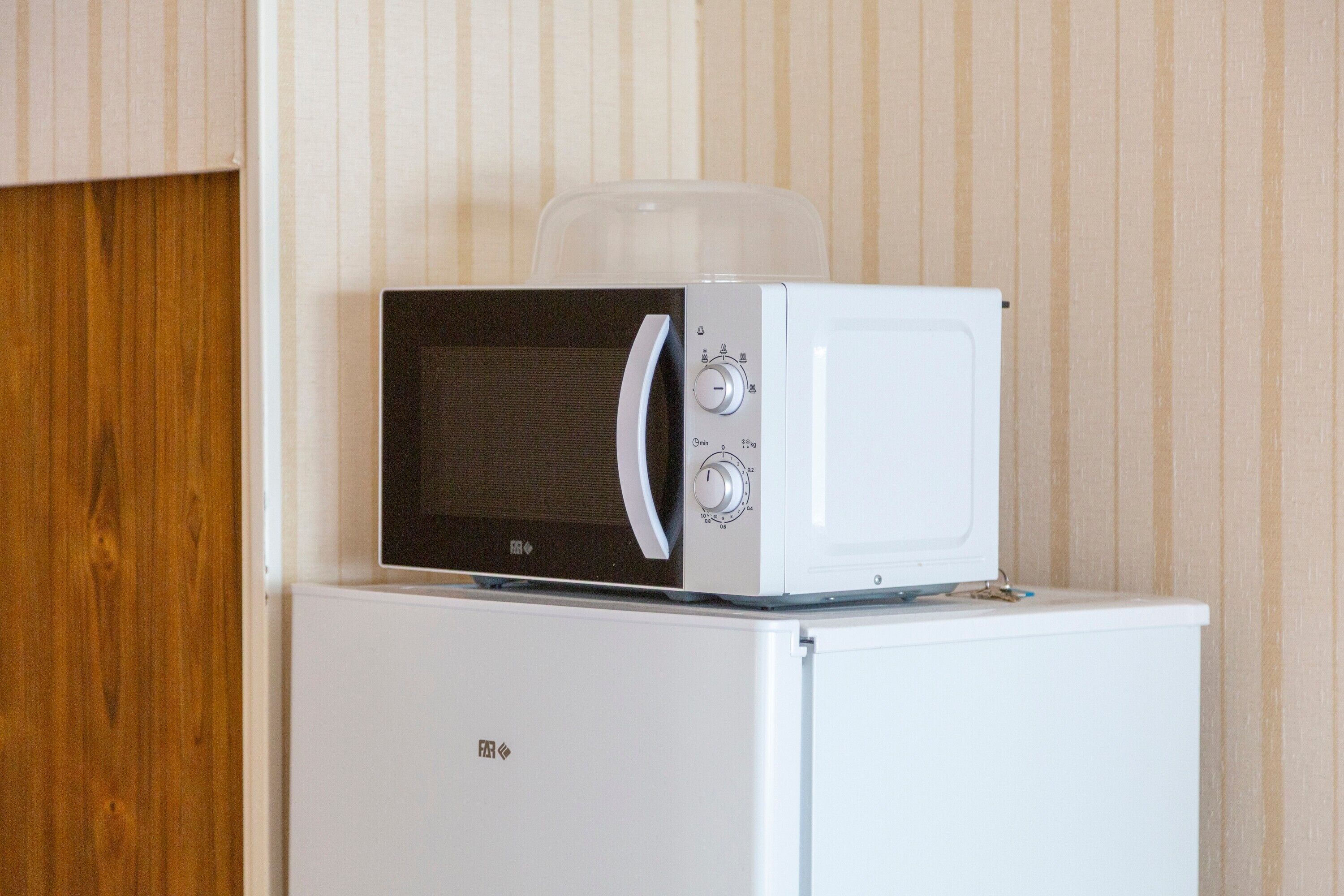 Un four à micro-ondes posé sur le dessus d’un réfrigérateur blanc.