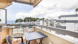 A balcony with a table and chairs, overlooking a residential area with multiple buildings and a clear sky. - Studio Apartment 'Vue Mer - 50m De La Plage' with Sea View, Private Terrace and Wi-Fi (Bénodet)