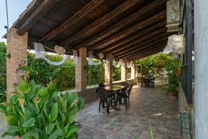 An outdoor patio with a brick wall, a covered wooden structure, and a table with chairs. - Country House 'Villa Ilusion' with Private Pool, Private Terrace and Wi-Fi (Agrupación de Mogon)