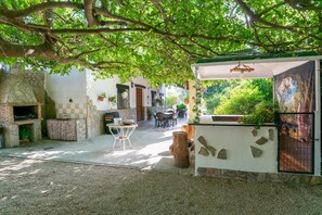 Un espace extérieur abrité, doté d’une cheminée en pierre, de tables et de chaises.