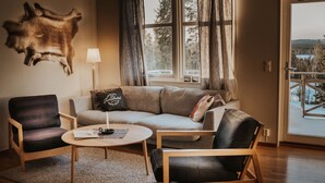 A cozy living room with a sofa, two armchairs, a coffee table, and a mounted animal head on the wall. - Vargen 2 by Interhome (Tännäskröket)