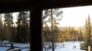 A cabin with a large window overlooking a snowy forest. - Vargen 2 by Interhome (Tännäskröket)