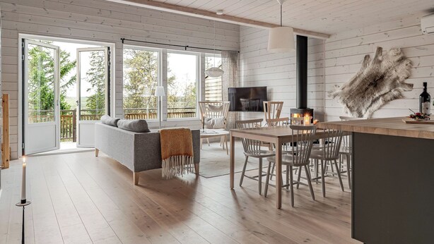Un interior moderno con piso de madera, un comedor con mesa y sillas, un sofá y una chimenea.