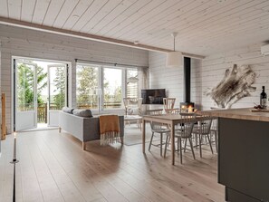 Un interior moderno con piso de madera, un comedor con mesa y sillas, un sofá y una chimenea.