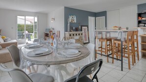 A modern kitchen with a dining area, featuring a round table with chairs, a kitchen counter, and a view of the outdoors. - Le Bas d'Anville by Interhome (Etaules)