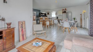 A spacious living area with a dining table, chairs, and a kitchen in the background. - Le Bas d'Anville by Interhome (Etaules)