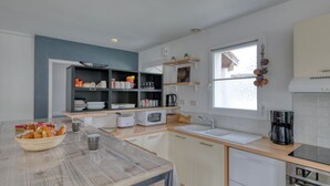 A modern kitchen with white cabinets, a wooden countertop, a built-in microwave, a sink, and a window with a view of the outside. - Le Bas d'Anville by Interhome (Etaules)