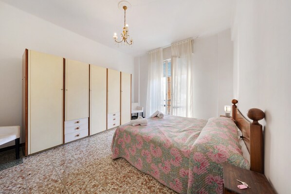 A bedroom with a bed, a wardrobe, a bench, and a nightstand.