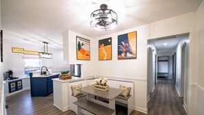 A modern kitchen with a built-in island, bench seating, and artwork on the walls. - The Nest:A Sanctuary of Nature & Luxury (Charlotte)